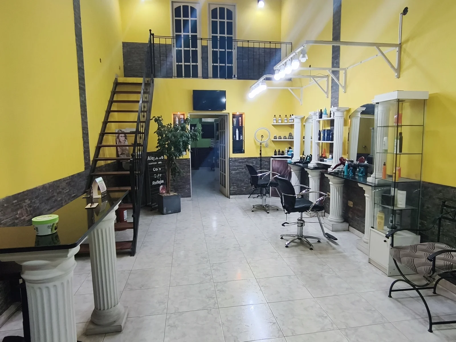 El salón entero visto desde la entrada: escalera, puestos de corte y sala de espera